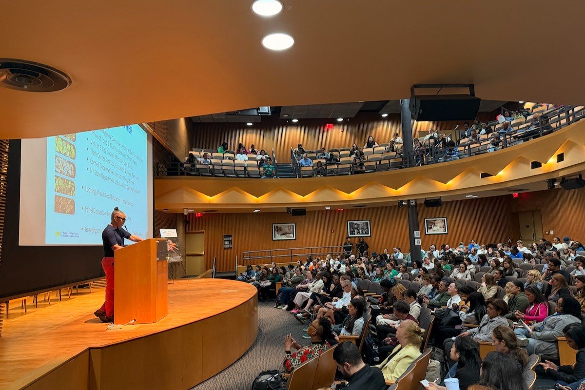 packed audtorium with a speaker at a podium